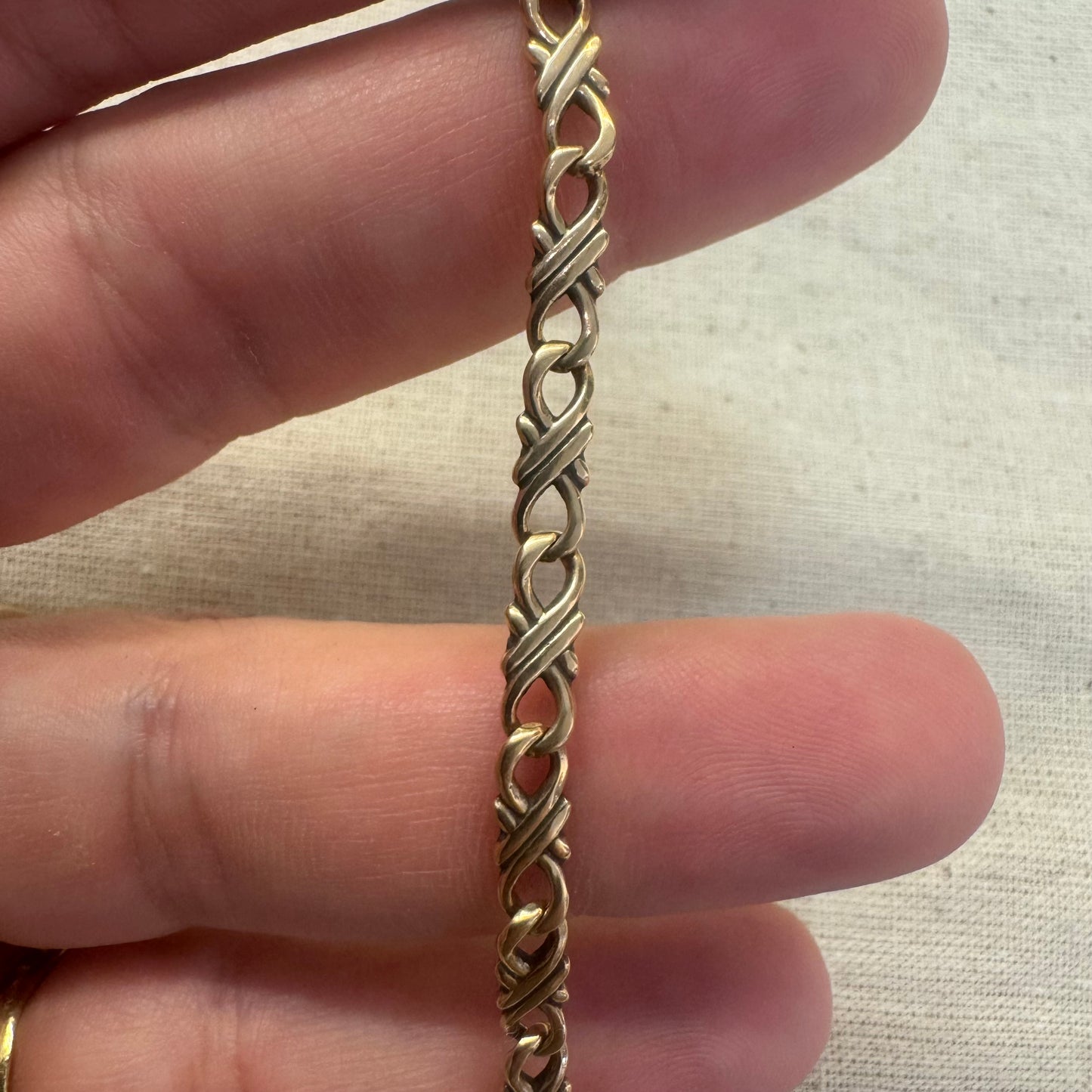 צמיד זהב צהוב 14 קראט עם חוליות שזורות בעיצוב שזירה ופיתול, וסוגר מסוג לובסטר.