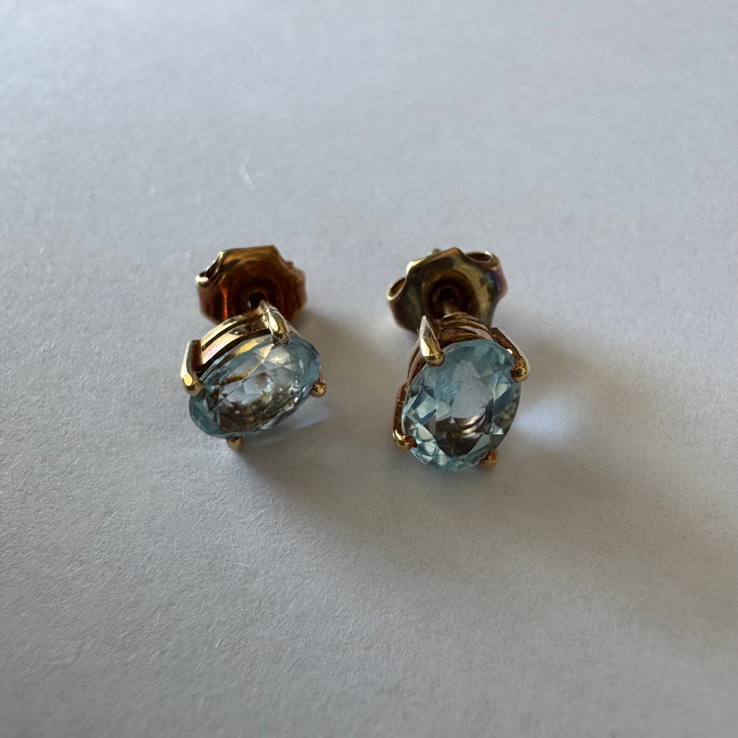 18K gold stud earrings set with oval-cut Aquamarines.