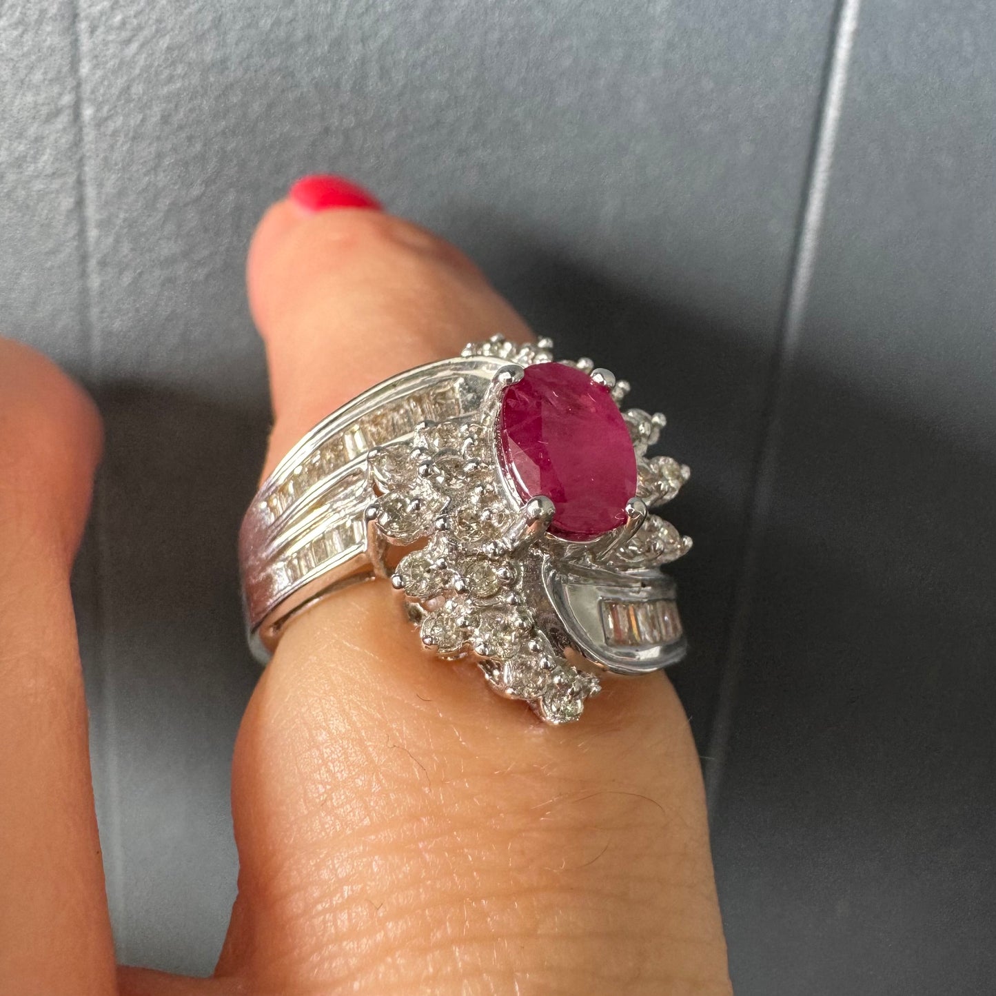 טבעת זהב 14 קראט משובצת אבן רובי אובלית בגוון אדום עמוק ומלא חיים ומוקפת הילה עשירה של יהלומים עגולים, המעניקים ברק ונוכחות מרשימה