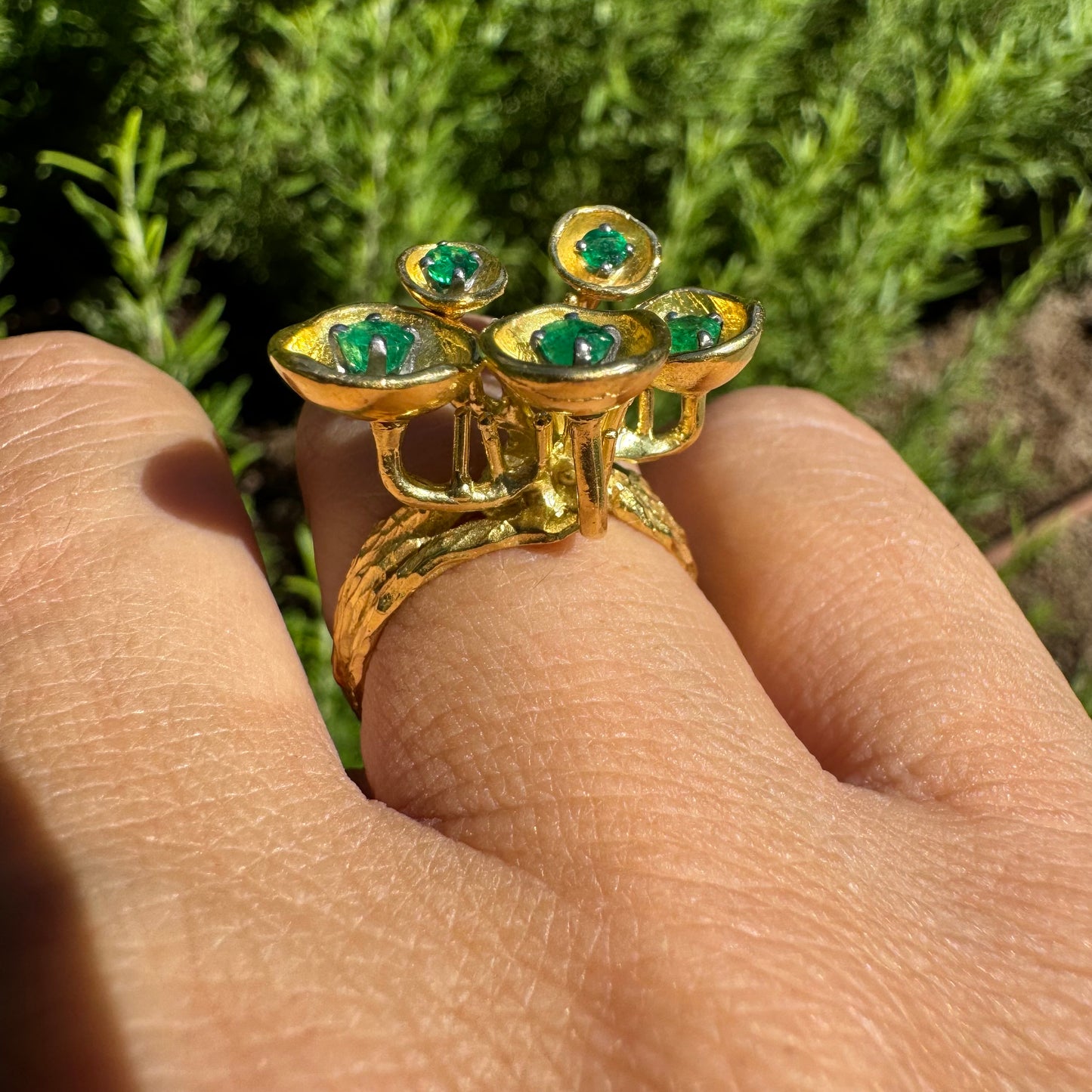 18K gold ring with an artistic floral-inspired design, set with round Emerald in textured circular settings.