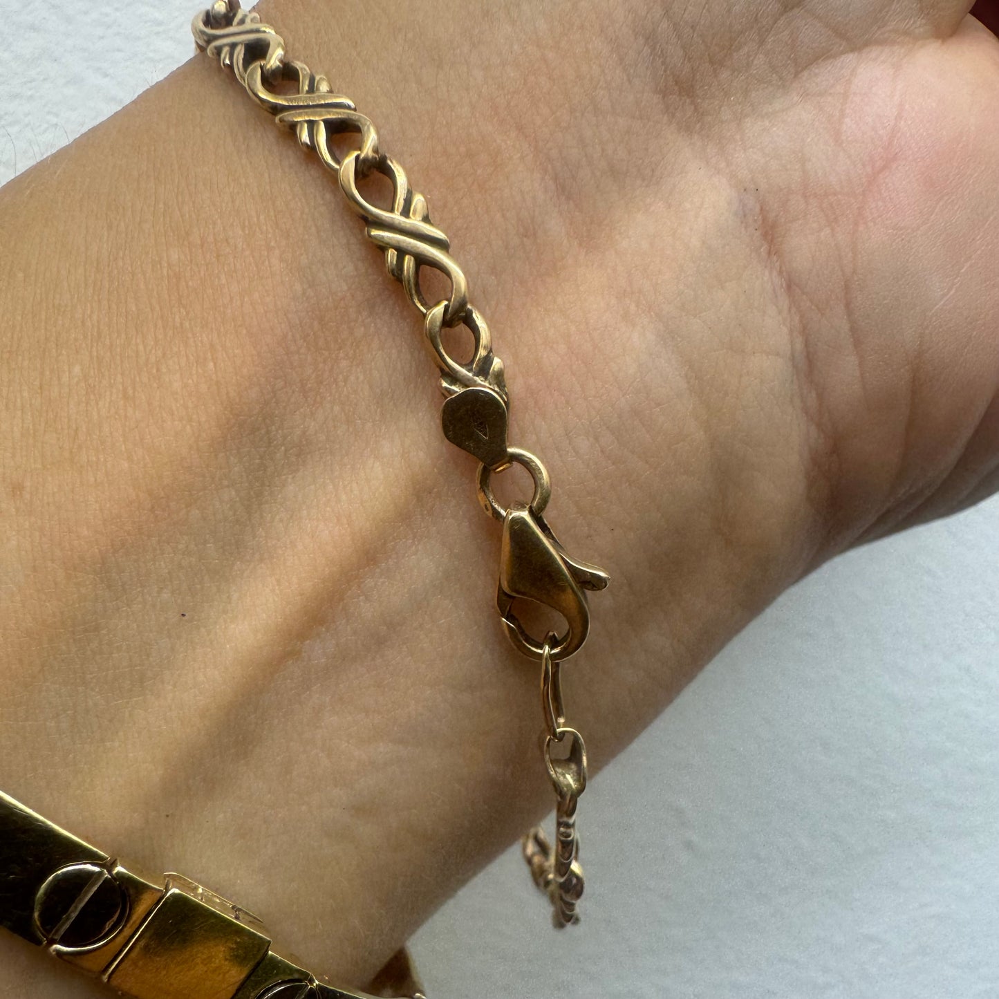 צמיד זהב צהוב 14 קראט עם חוליות שזורות בעיצוב שזירה ופיתול, וסוגר מסוג לובסטר.