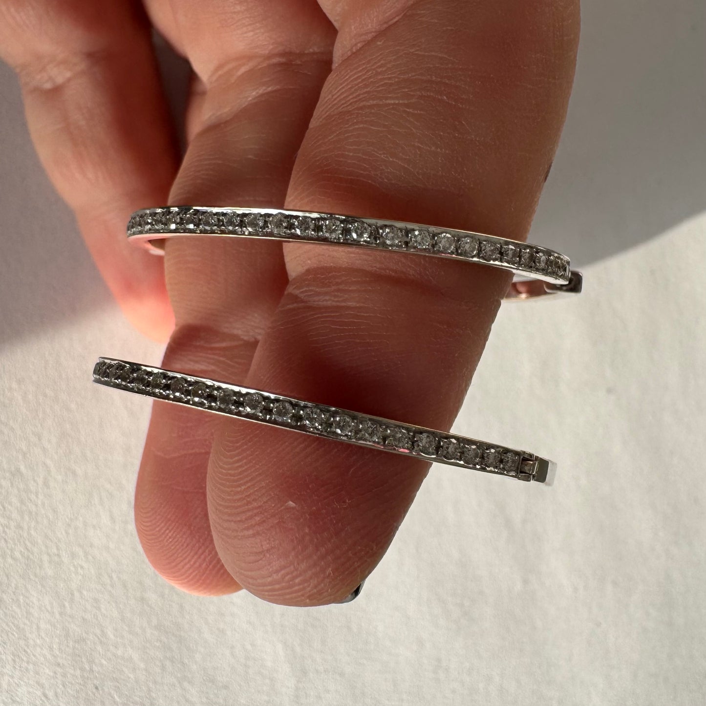 עגילי חישוק זהב 18 קראט, משובצים יהלומים לכל אורכם בחזית ובחלק הפנימי.