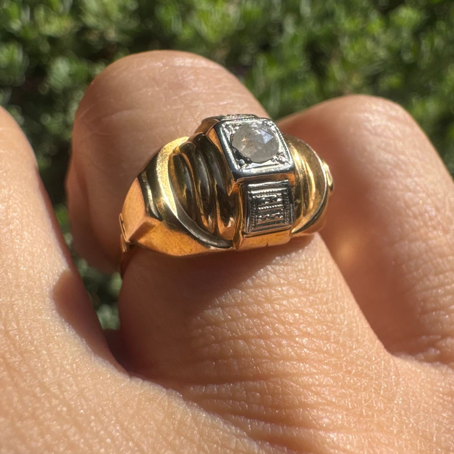 18K gold ring featuring a central round Diamond set in a square bezel with decorative details.