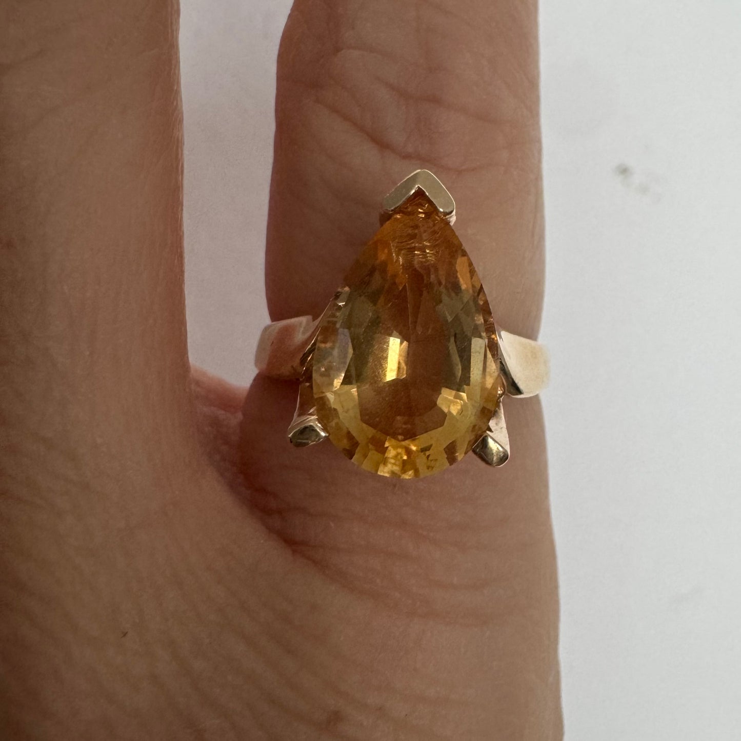 טבעת זהב צהוב 14 קראט משובצת באבן סיטרין גדולה בחיתוך טיפה, עם זהב שמחבק אותה בצורה פתוחה ומודרנית.