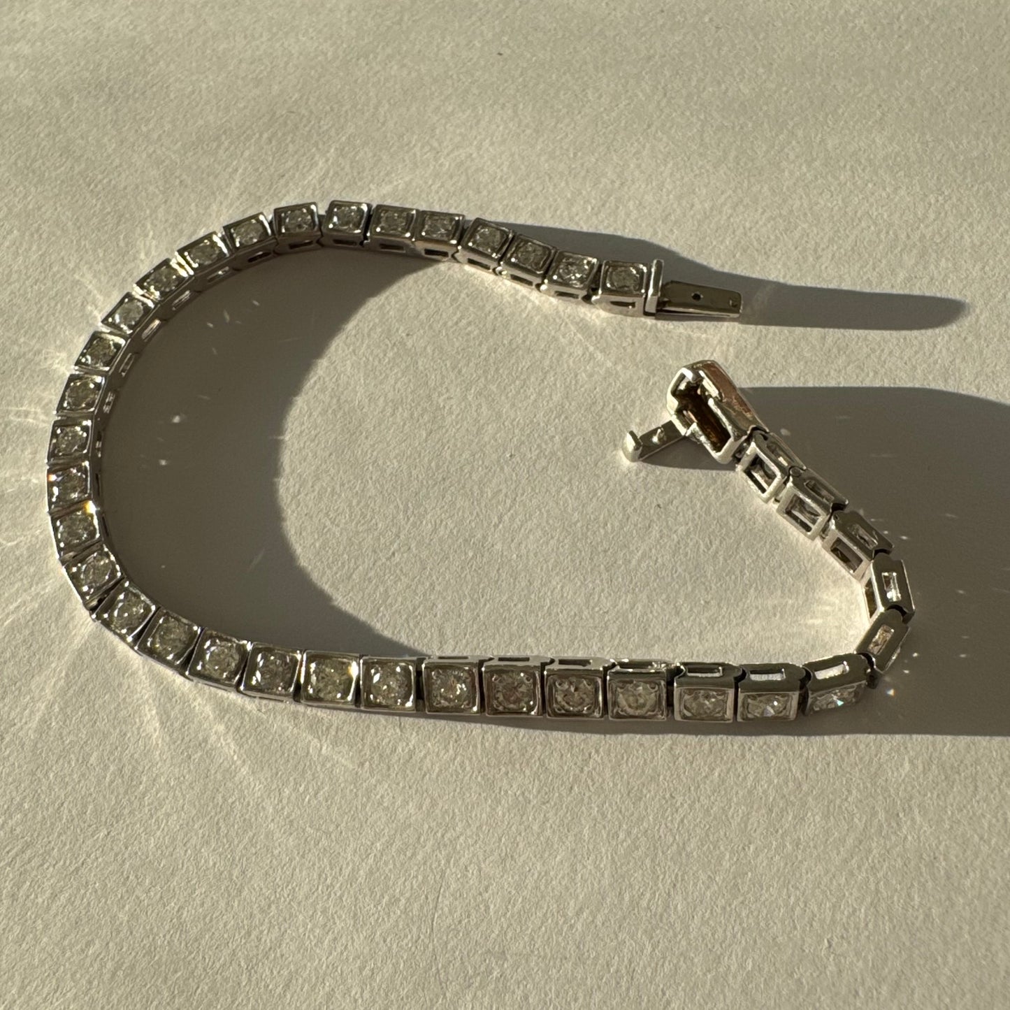 צמיד טניס זהב לבן 18 קראט משובץ יהלומים עגולים נוצצים בתוך מסגרות ריבועיות.