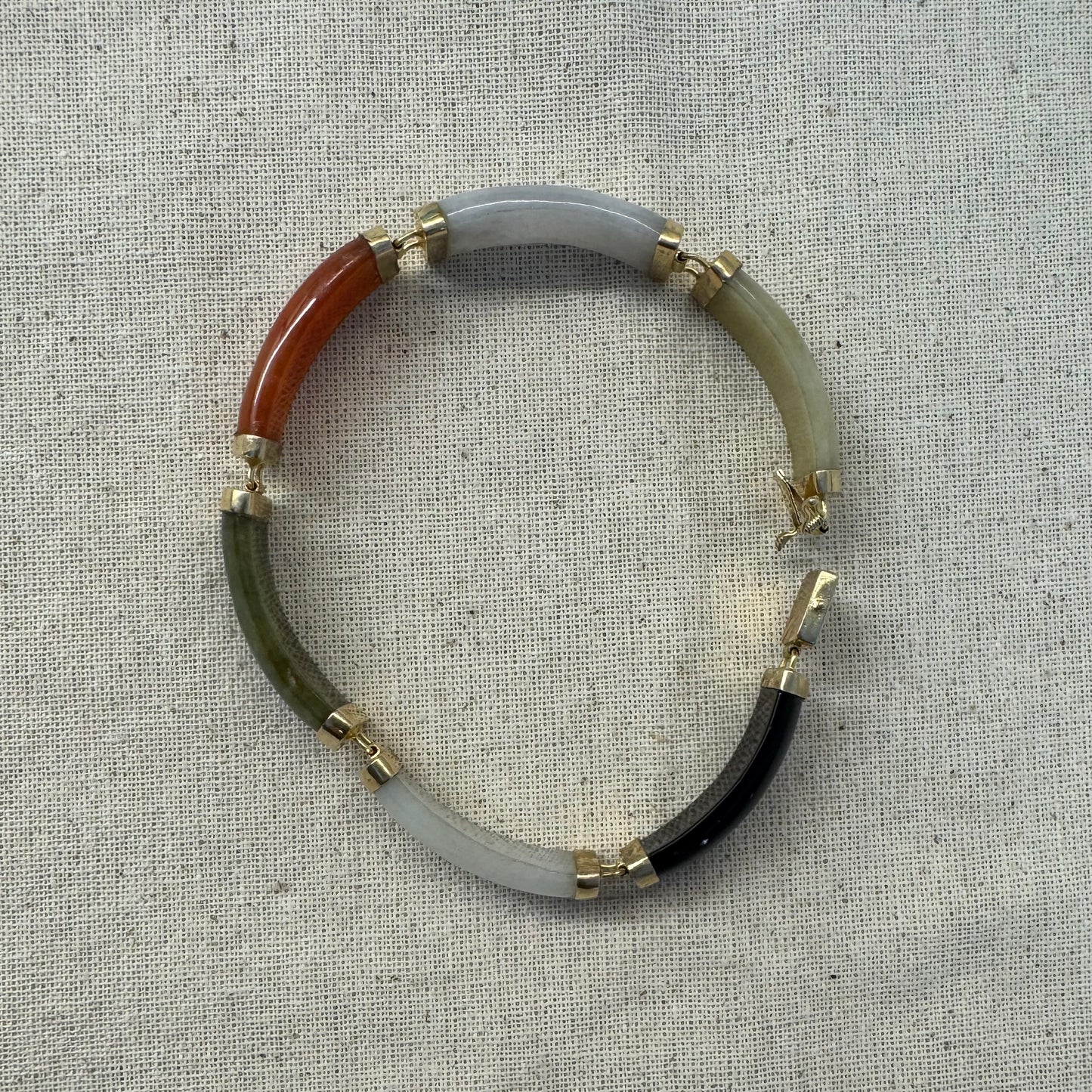 צמיד זהב צהוב 14 קראט עשוי מקטעי ג’ייד (jade) בשלושה גוונים – ירקרק, לבן ואדום – בשיבוץ זהב.