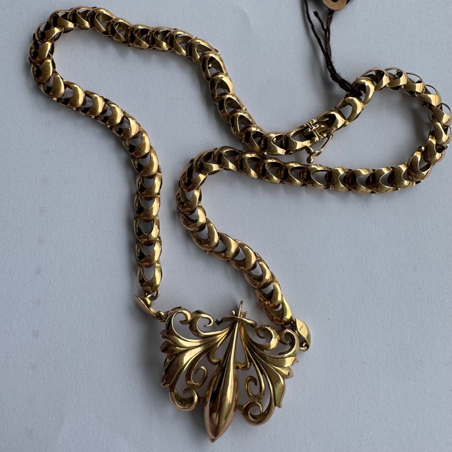 שרשרת זהב 14 קראט בעלת עיטור פלר דה ליס (Fleur-de-lis) אמנותי, המעוצב בקווים מעוגלים של עלי שושן בסגנון אר נובו.