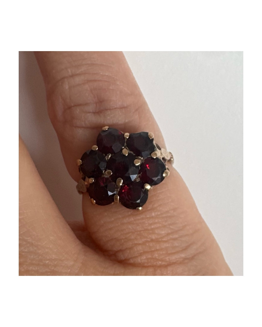 טבעת זהב 9 קראט משובצת אבני גרנט בגוון אדום עמוק בעיצוב פרח.
