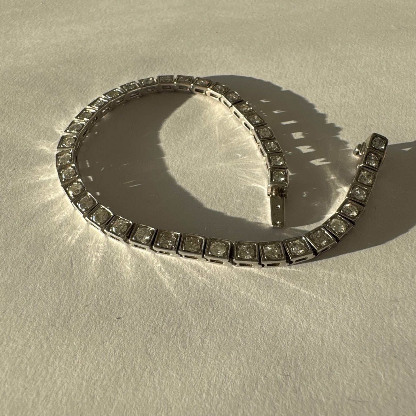 צמיד טניס זהב לבן 18 קראט משובץ יהלומים עגולים נוצצים בתוך מסגרות ריבועיות.