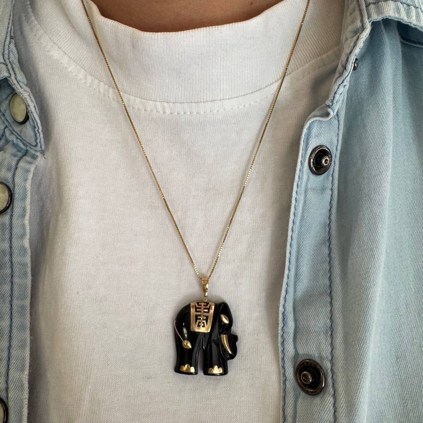 תליון זהב 9 קראט בעיצוב ייחודי ומלא נוכחות של פיל אפריקאי, המשלב גוף שחור מלוטש עם עיטורי זהב עדינים.