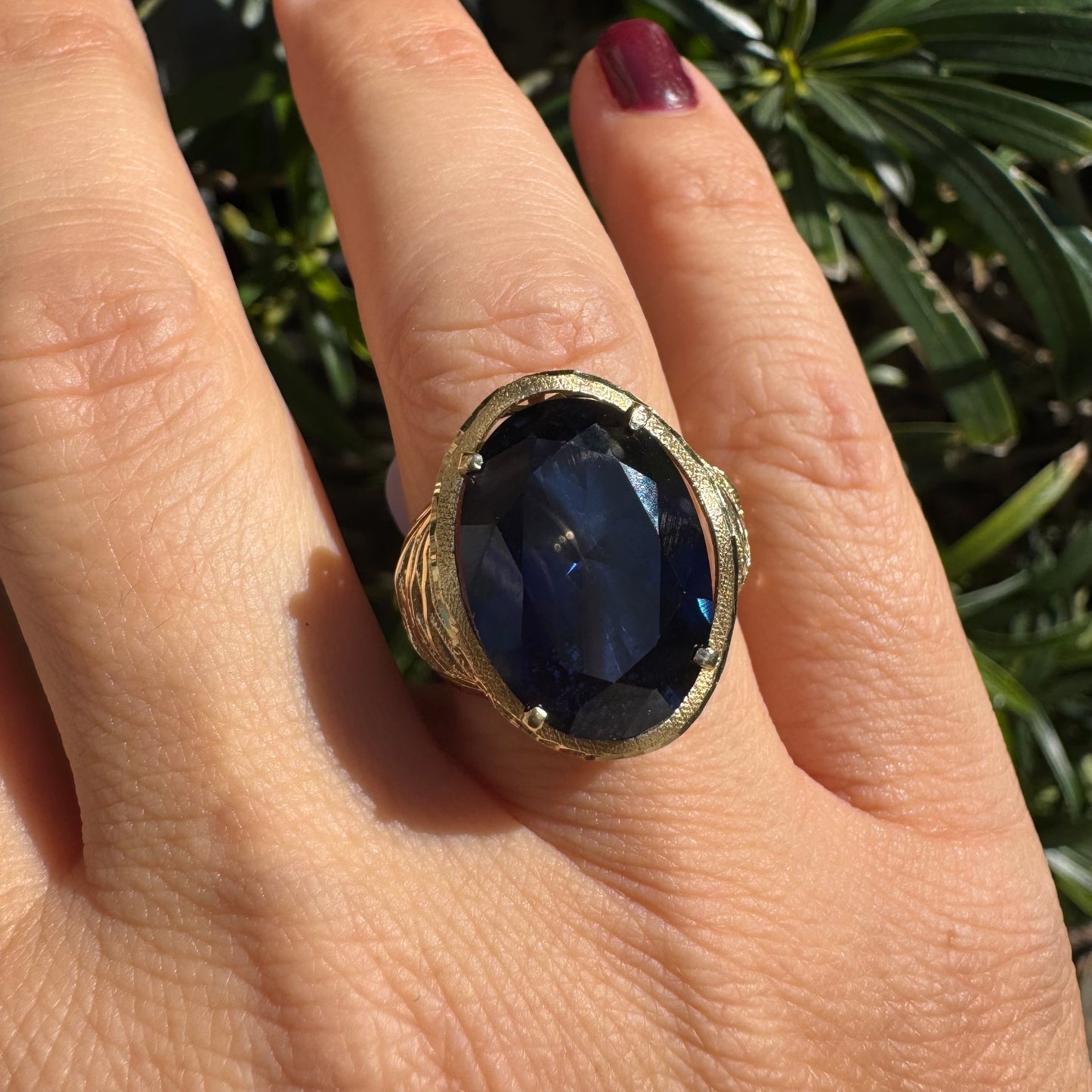 14K gold ring set with a deep navy-blue oval Sapphire in a dramatic openwork setting
