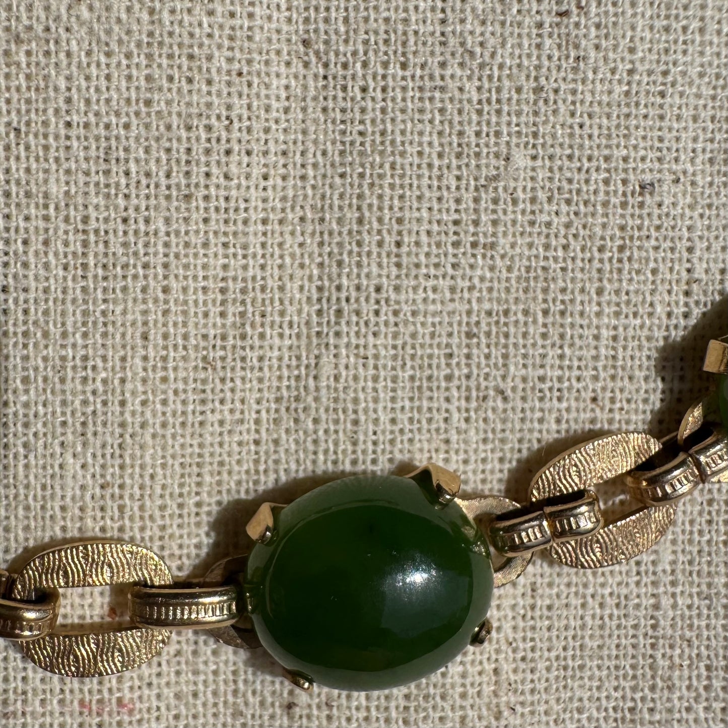 צמיד זהב צהוב 14 קראט משובץ באבני ג’ייד ירוקות בחיתוך קבושון (cabochon) בעיצוב אליפטי, המחוברות ביניהן בחוליות זהב עם טקסטורה מעניינת.