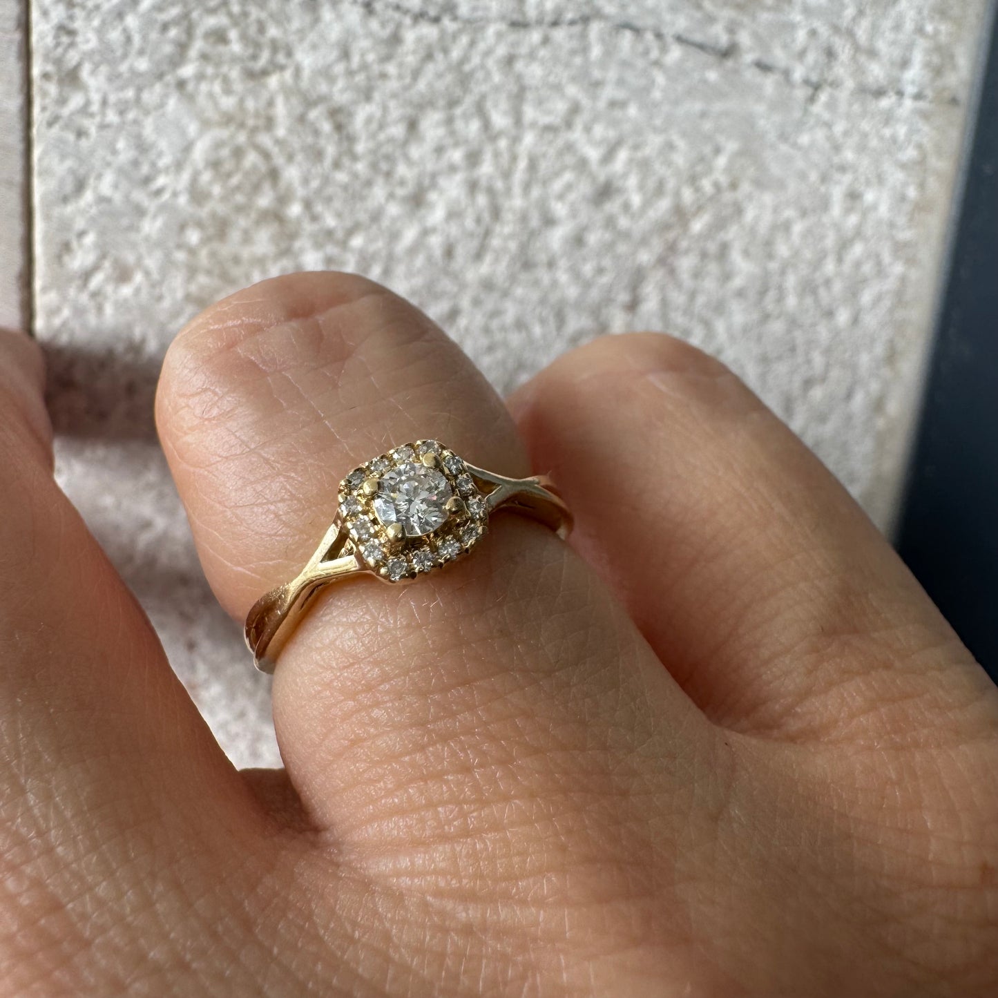 טבעת זהב 14 קראט משובצת יהלום מרכזי עגול ומבריק, מוקף הילה עדינה של יהלומים המעצימים את הברק