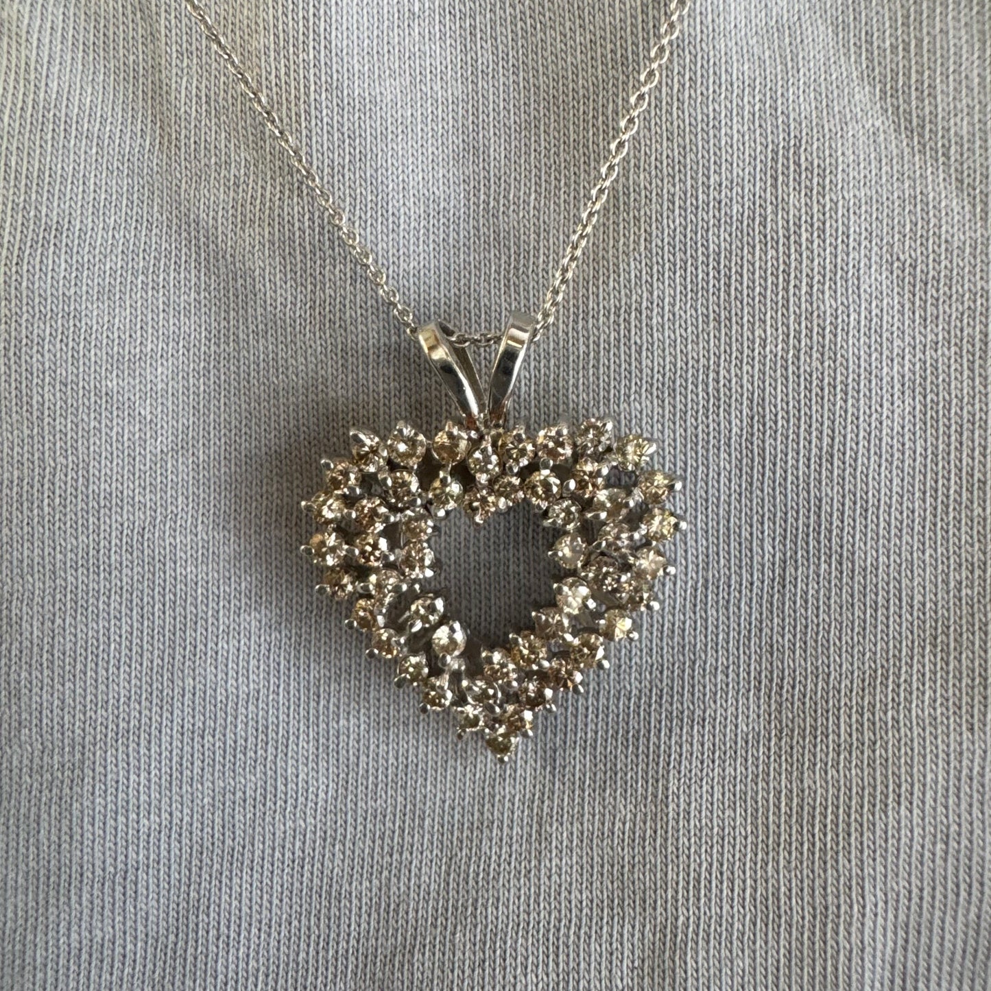 תליון לב זהב לבן 14 קראט, משובץ יהלומים בשיבוץ שיניים עדין היוצר מראה עשיר ומלא ברק.