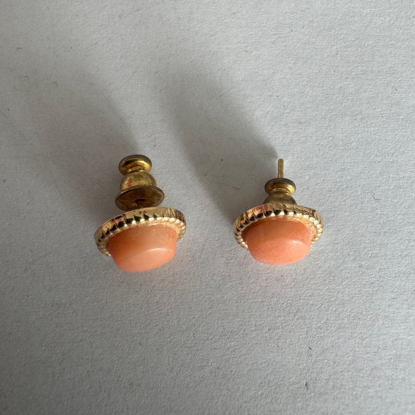 14K gold stud earrings set with natural Coral stones in a soft peach-pink tone.