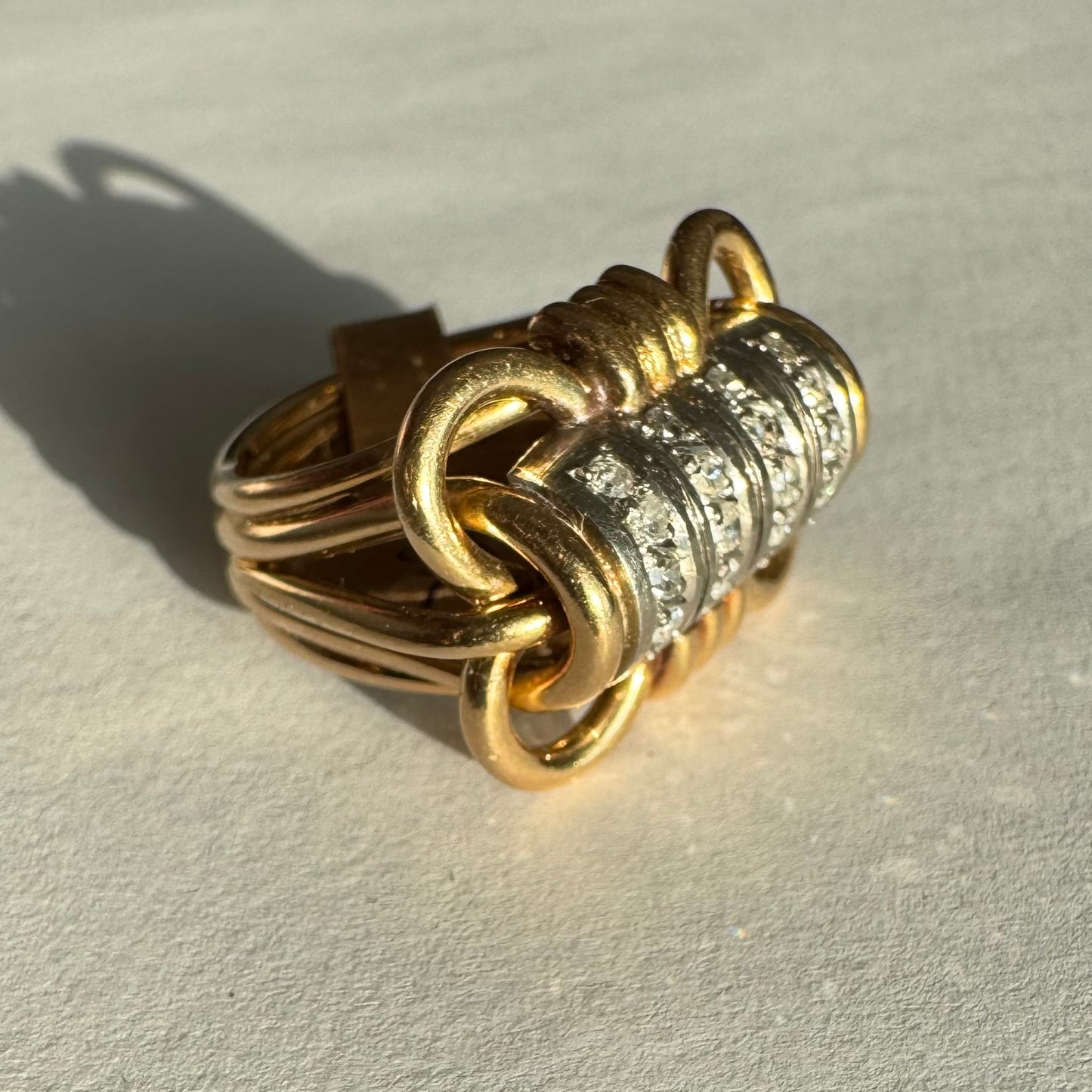 טבעת זהב צהוב ולבן 18 קראט עם מרכז בצורת חבית, משובצת יהלומים נוצצים.