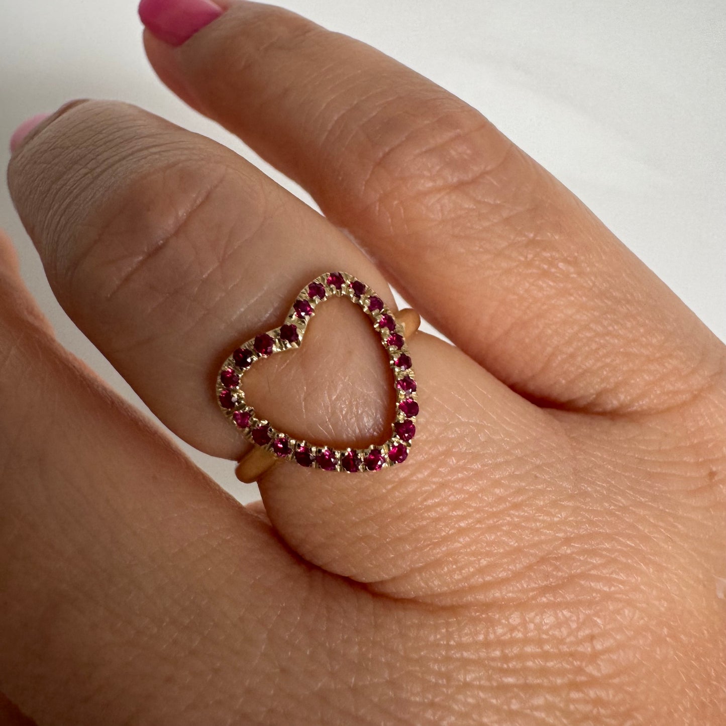 14K yellow gold open-heart ring set with deep red rubies along the frame.