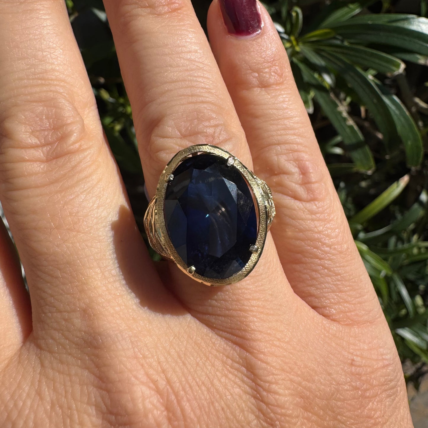 14K gold ring set with a deep navy-blue oval Sapphire in a dramatic openwork setting