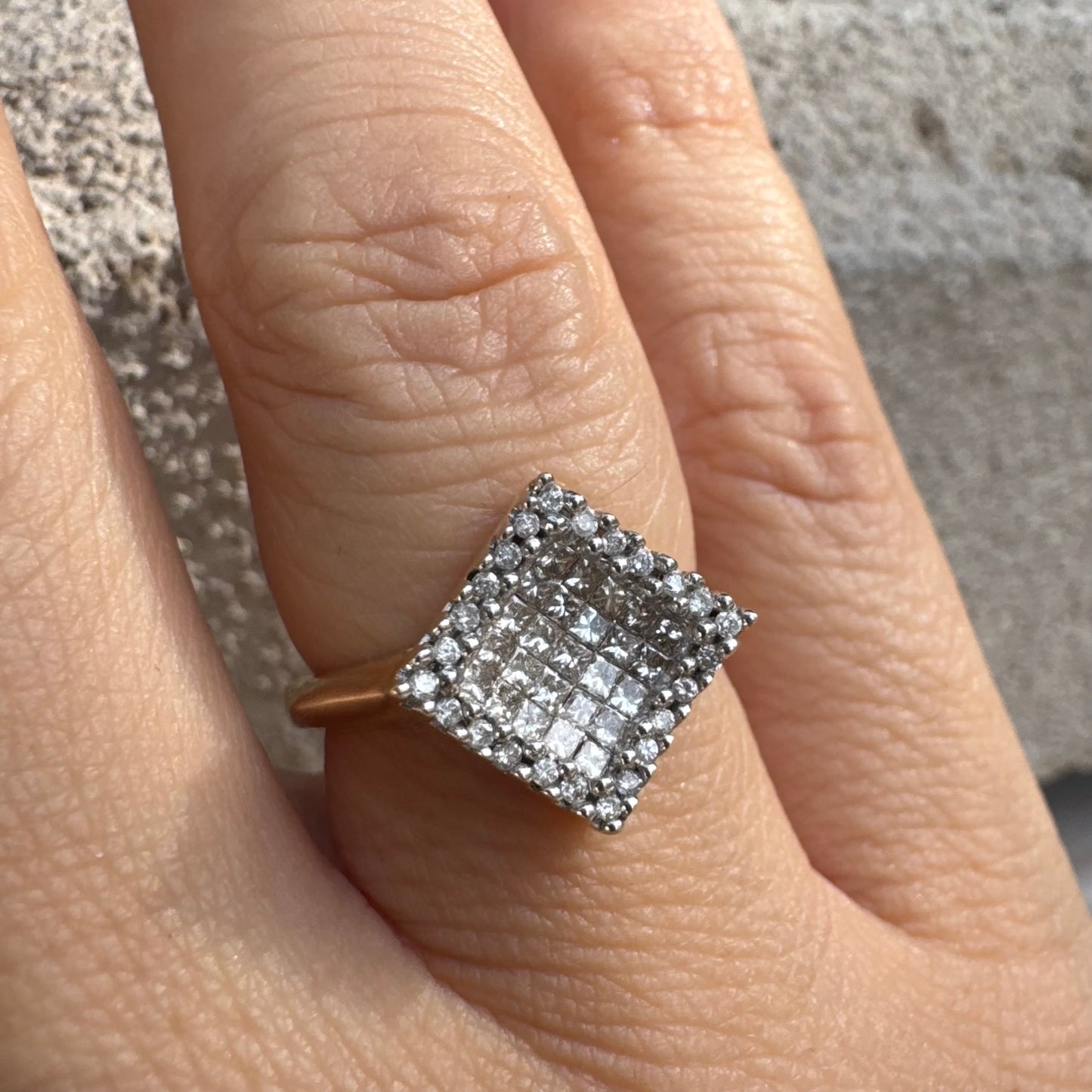 טבעת זהב 14 קראט בעיצוב ריבועי משובצת יהלומים בחיתוך פרינסס ומוקפת מסגרת יהלומים עגולים. 