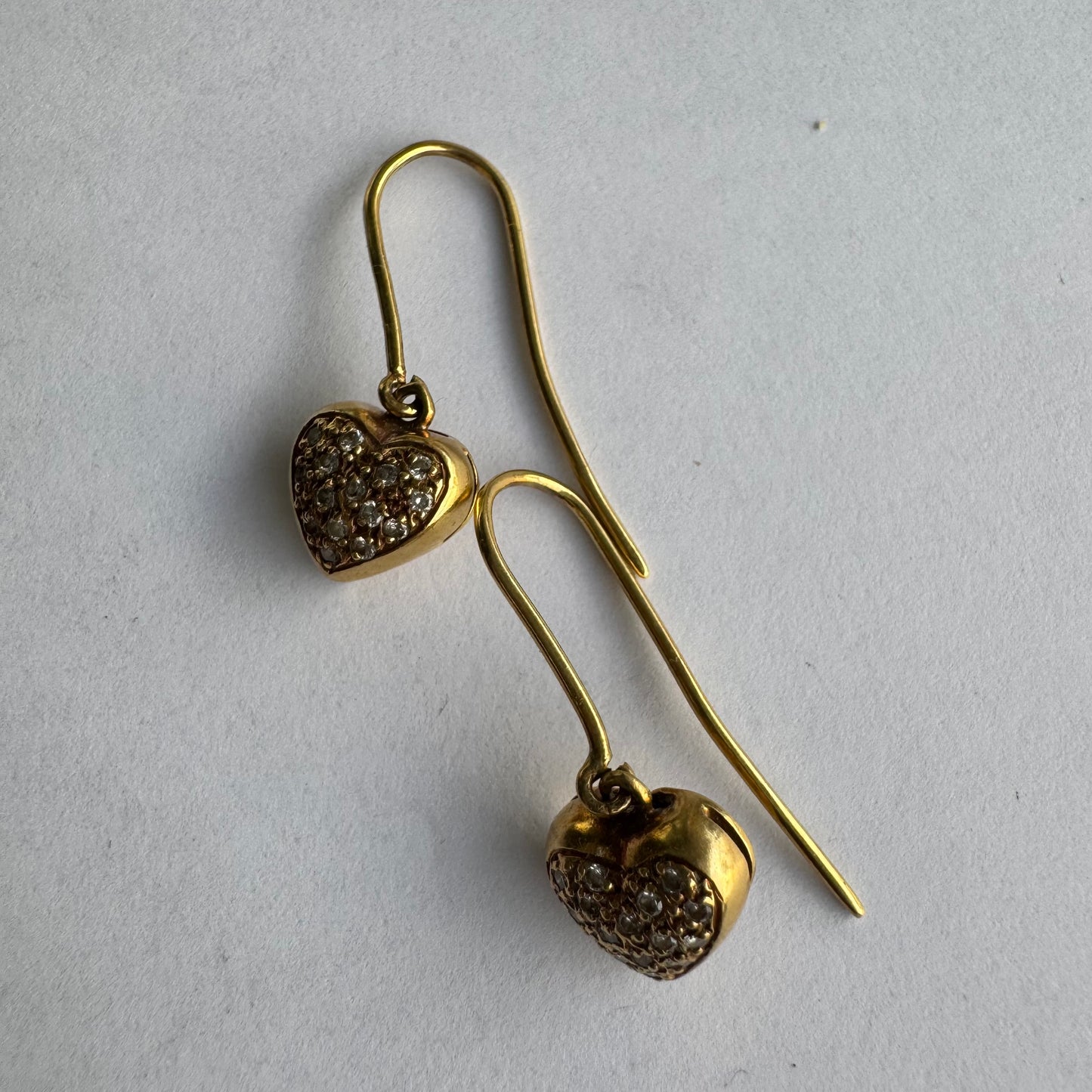 עגילי זהב צהוב 18 קראט תלויים בצורת לב, משובצים יהלומים קטנים המוסיפים ברק עדין ונוכחות אלגנטית.