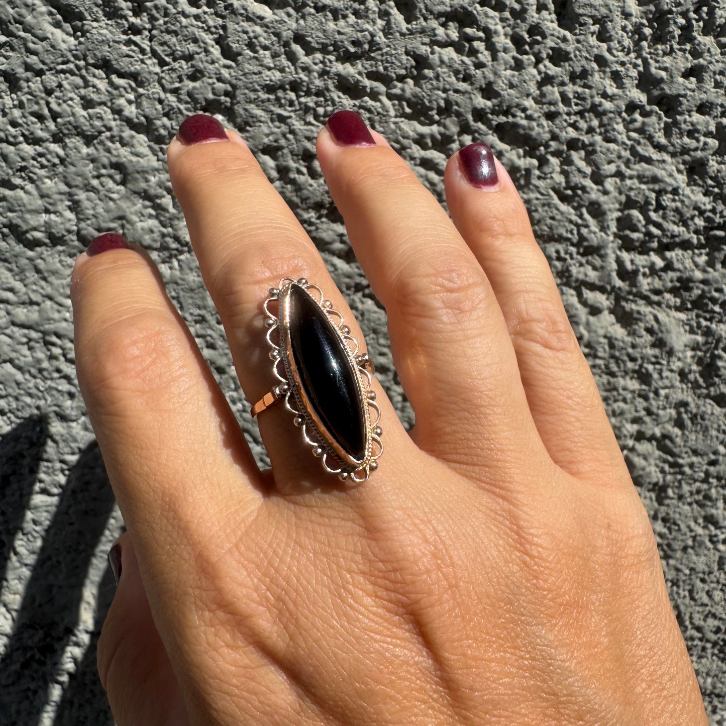 14K gold ring featuring a long marquise-shaped black Onyx stone, framed with delicate decorative details around the setting.