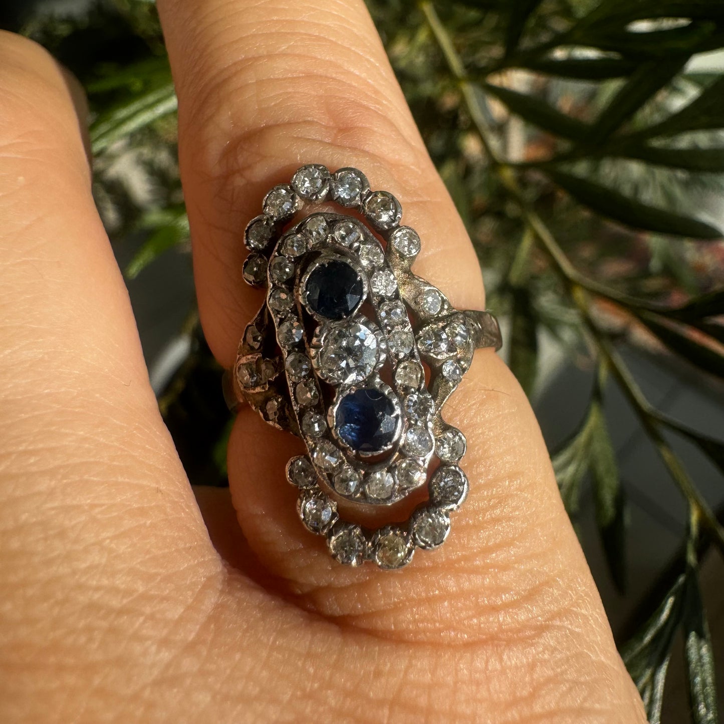 14K gold Antique featuring a stunning trio of gemstones - two deep blue Sapphires surrounding a brilliant old-cut Diamonds