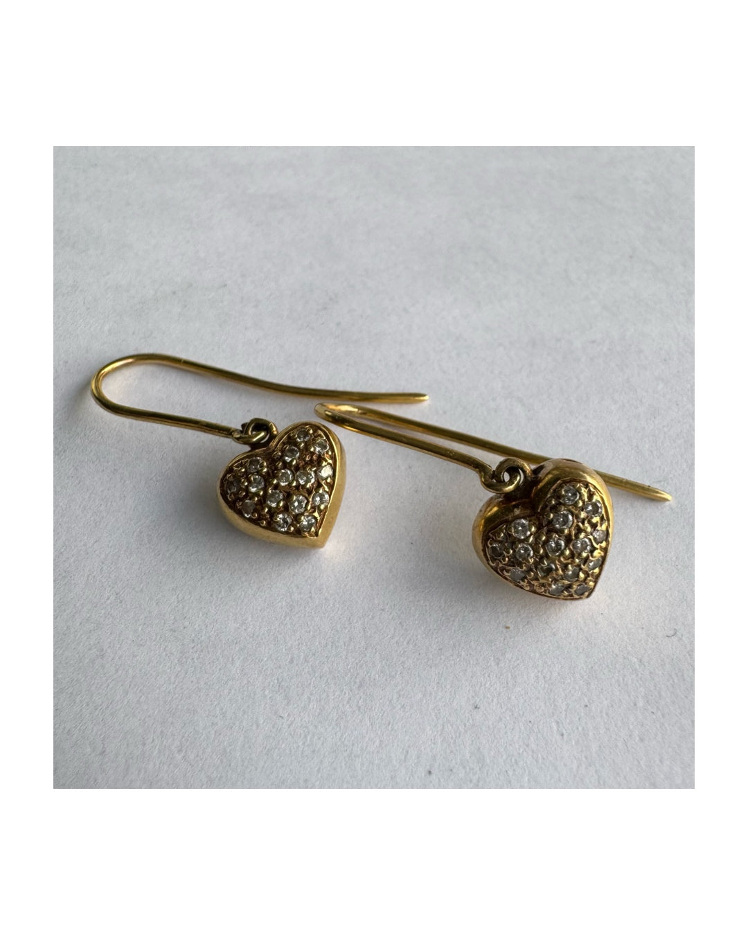 עגילי זהב צהוב 18 קראט תלויים בצורת לב, משובצים יהלומים קטנים המוסיפים ברק עדין ונוכחות אלגנטית.