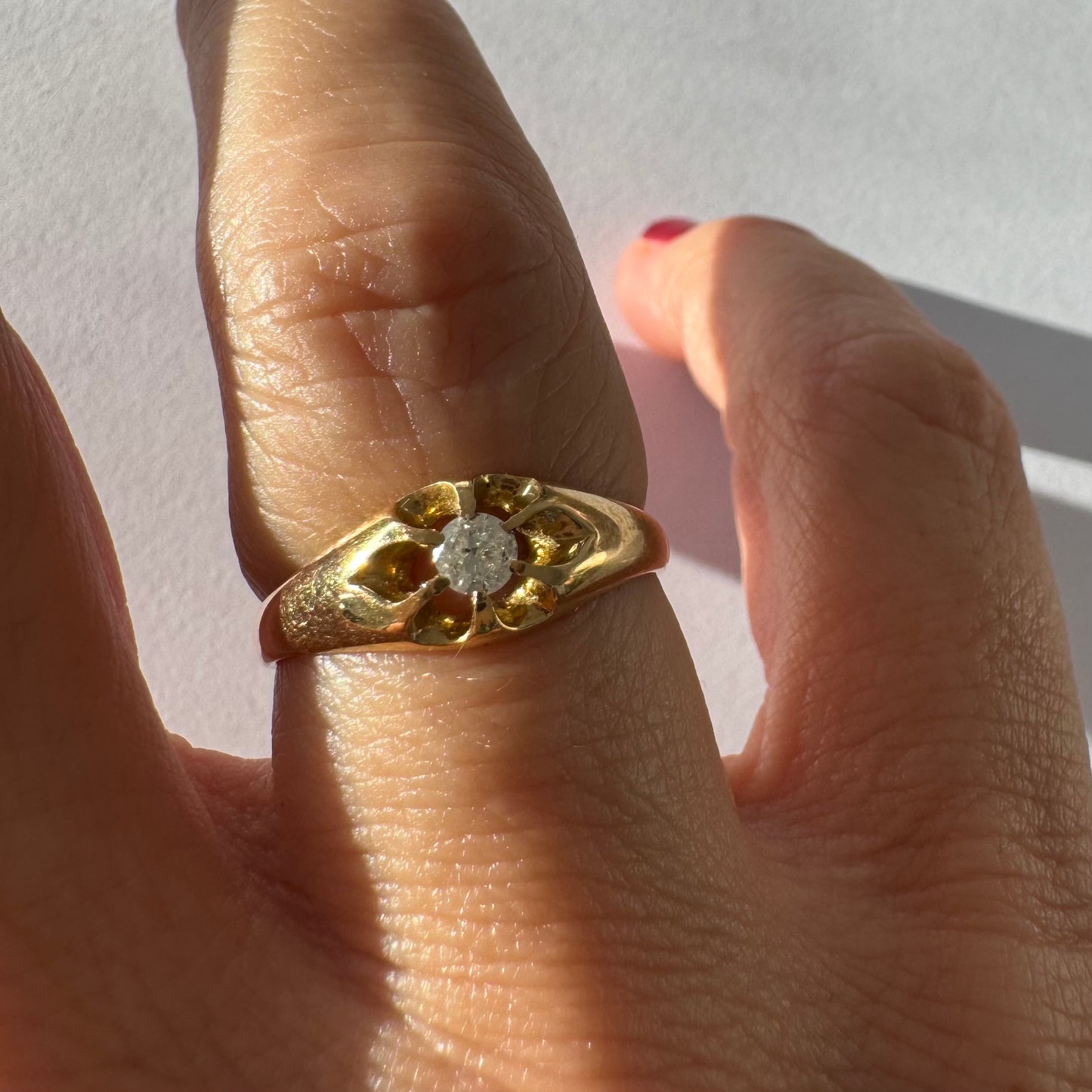 טבעת זהב צהוב 18 קראט בעיצוב פרח עדין, משובצת יהלום מרכזי בתוך עלי כותרת פתוחים.