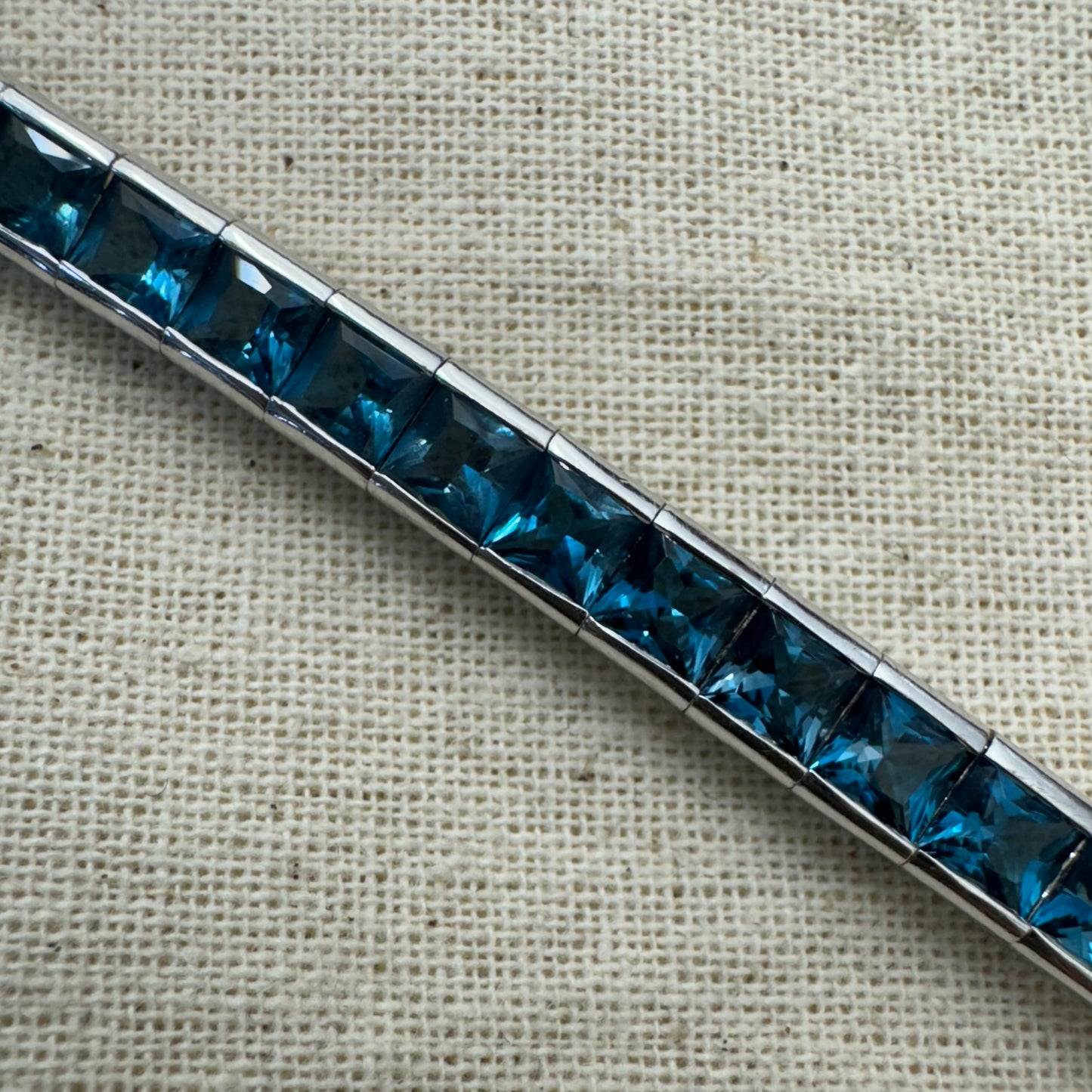 צמיד זהב לבן 18 קראט של המותג ה.שטרן משובץ אבני טופז כחולה&nbsp;בשיבוץ ערוץ חלק וקלאסי – פריט נצחי עם טאץ’ מודרני