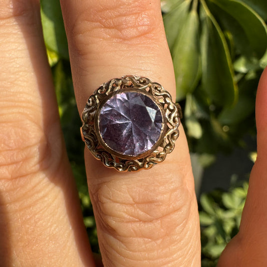 14K gold ring set with a large round-cut Tanzanite framed by an ornate filigree bezel