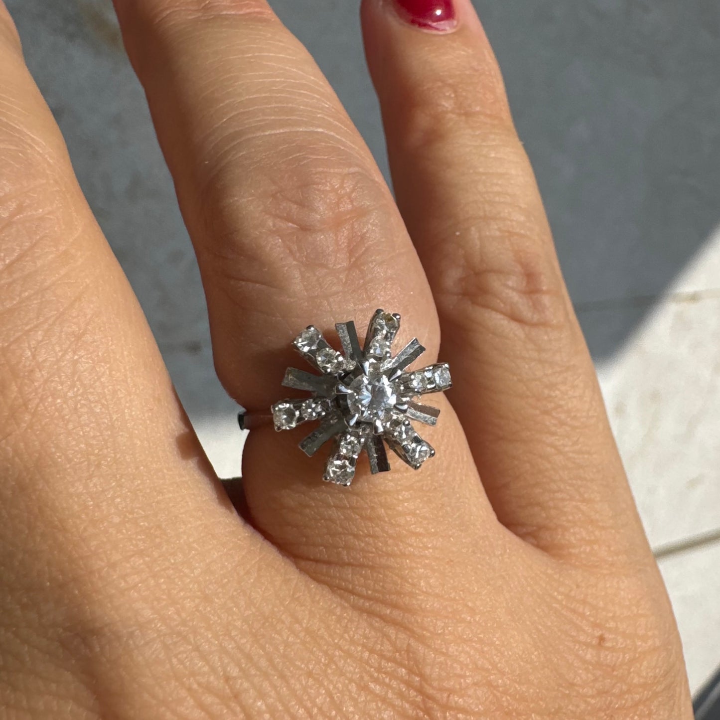 טבעת זהב לבן 18 קראט בעיצוב קרני שמש מרהיב, משובצת יהלומים הלוכדים את האור מכל כיוון. 