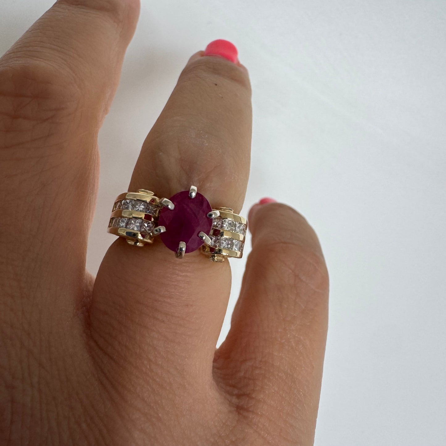 טבעת זהב צהוב 14 קראט משובצת אבן רובי טבעית מרכזית בגוון אדום עמוק ומוקפת שורות יהלומים טבעיים משני הצדדים.
