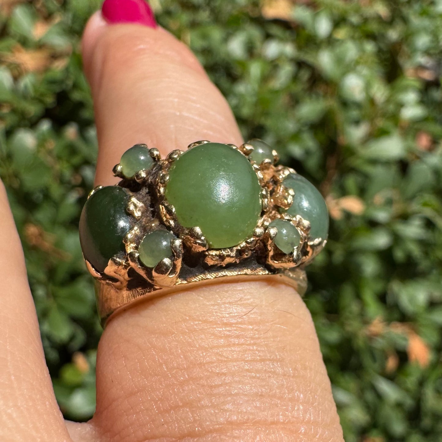 14K gold ring set with a central oval green Jade cabochon, framed by additional Jade stones in varying shades and sizes