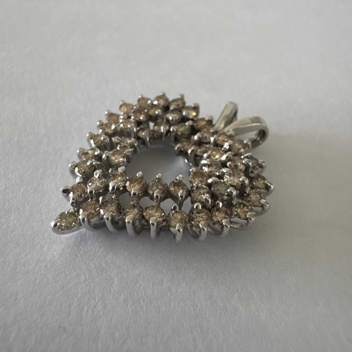 תליון לב זהב לבן 14 קראט, משובץ יהלומים בשיבוץ שיניים עדין היוצר מראה עשיר ומלא ברק.