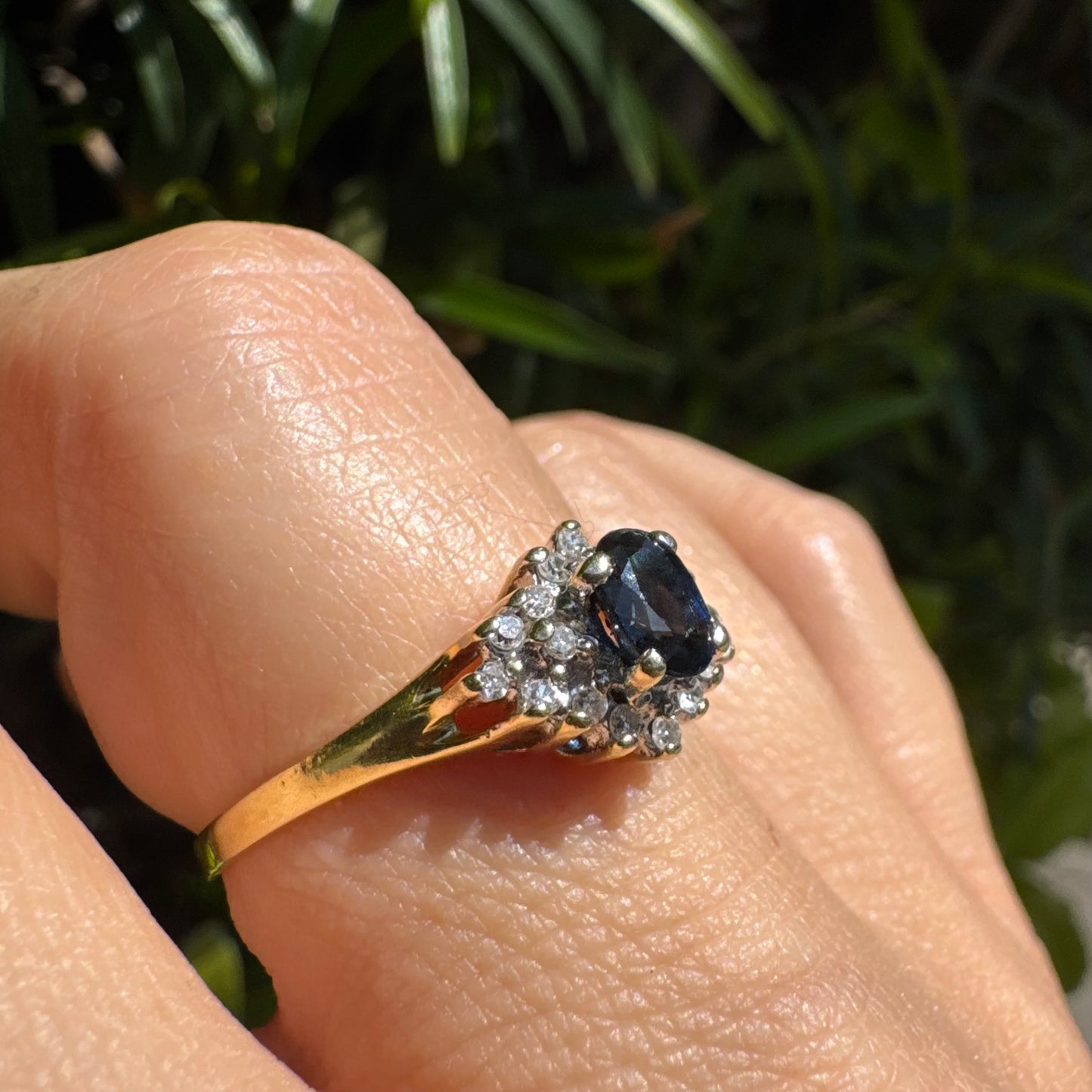 14K gold ring set with an oval blue Sapphire surrounded by sparkling Diamonds