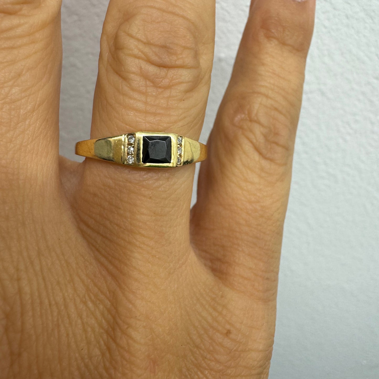 טבעת זהב 14 קראט משובצת אבן ספינל שחור בחיתוך ריבועי במרכז ויהלומים קטנים משני הצדדים.