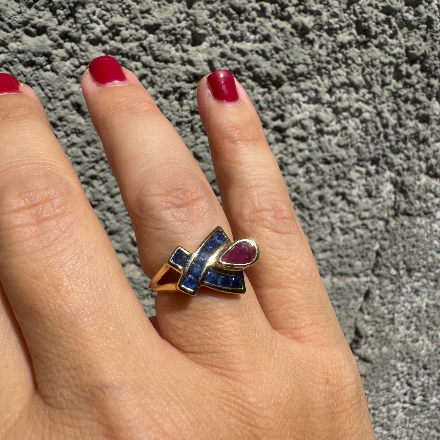 10K gold ring set with a pear-shaped Ruby and deep blue Sapphires in a geometric design.