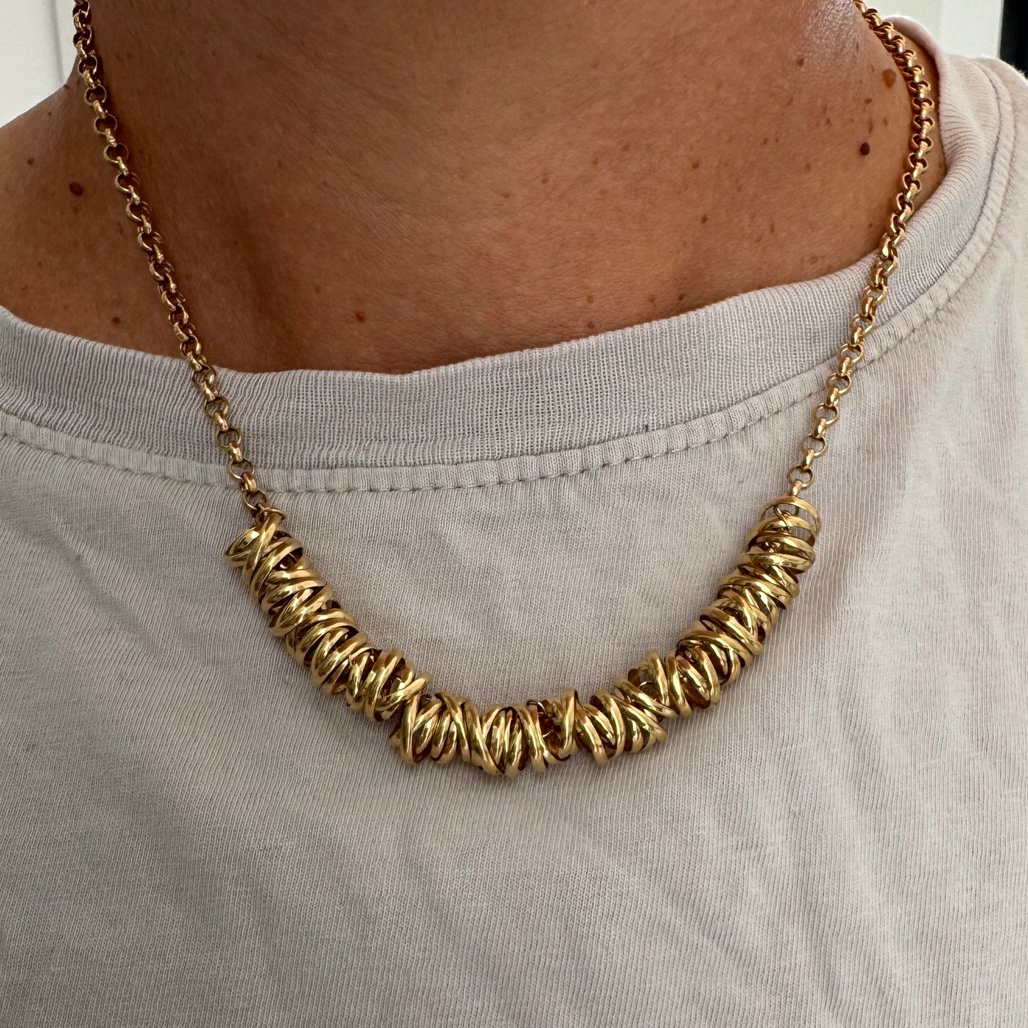 14K gold necklace featuring a series of intertwined gold rings creating a bold and sculptural design.