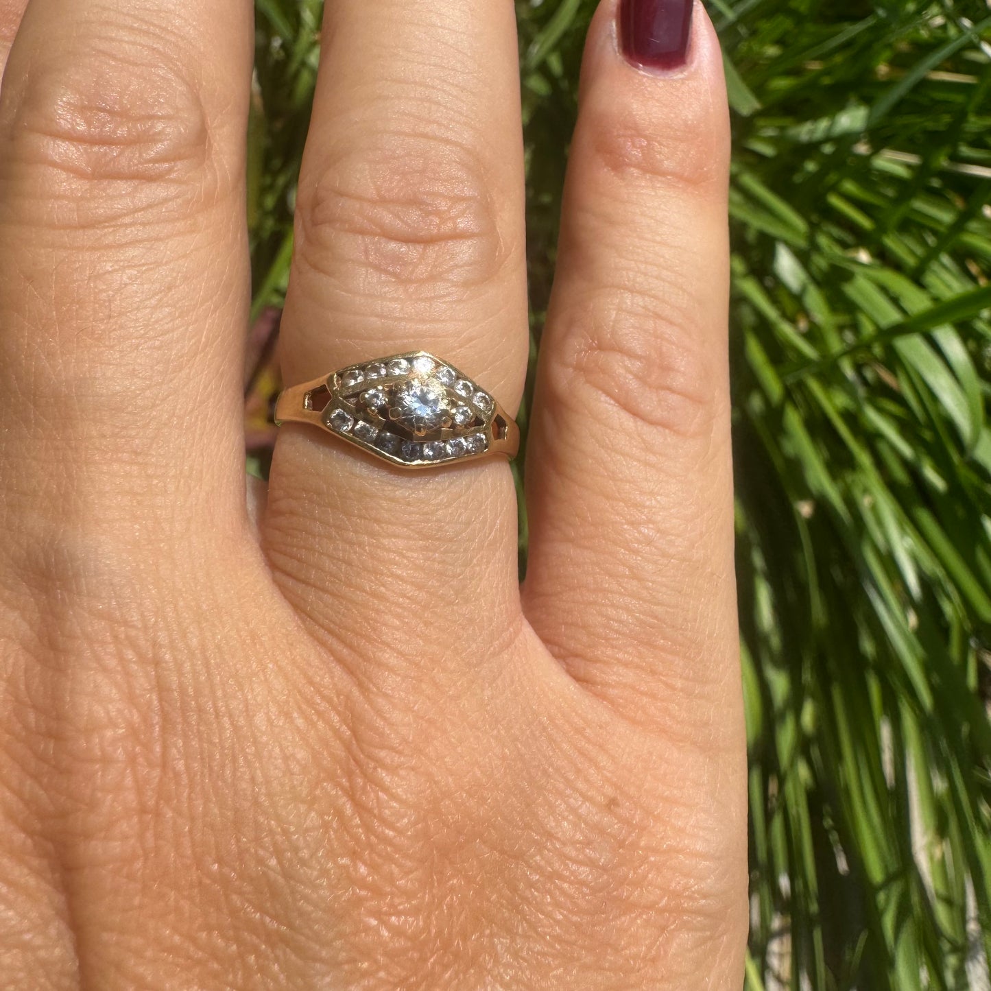 18K gold ring set with a central round Diamond, surrounded by rows of Diamonds in a decorative setting.