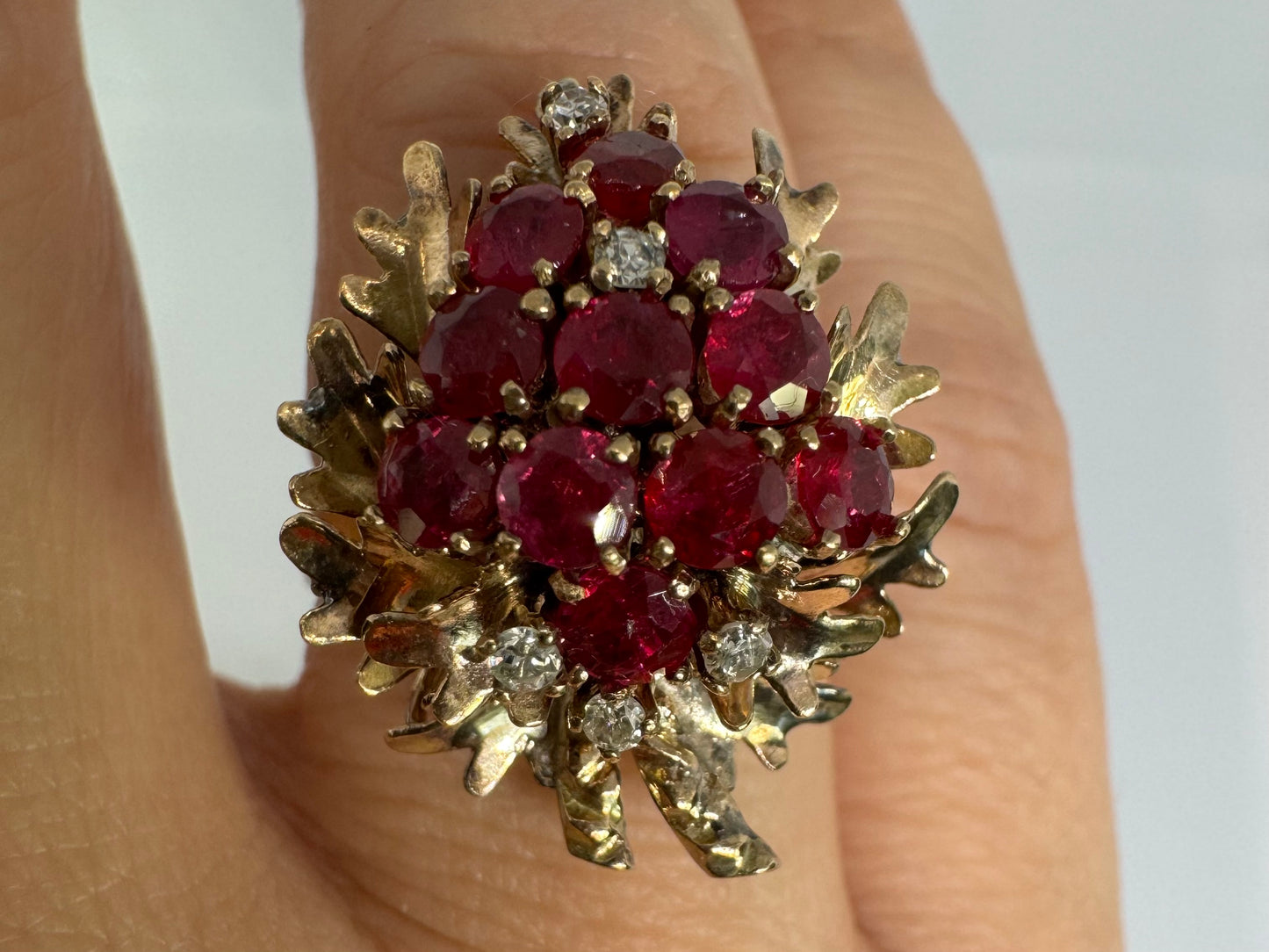 14K gold ring set with a vibrant cluster of deep red rubies and sparkling diamonds.