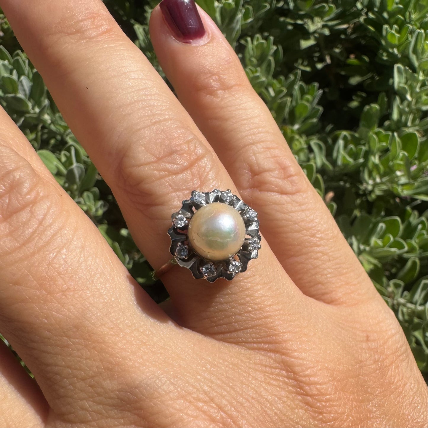 18K gold ring set with a round Pearl at the center, surrounded by a floral halo set with small Diamonds.