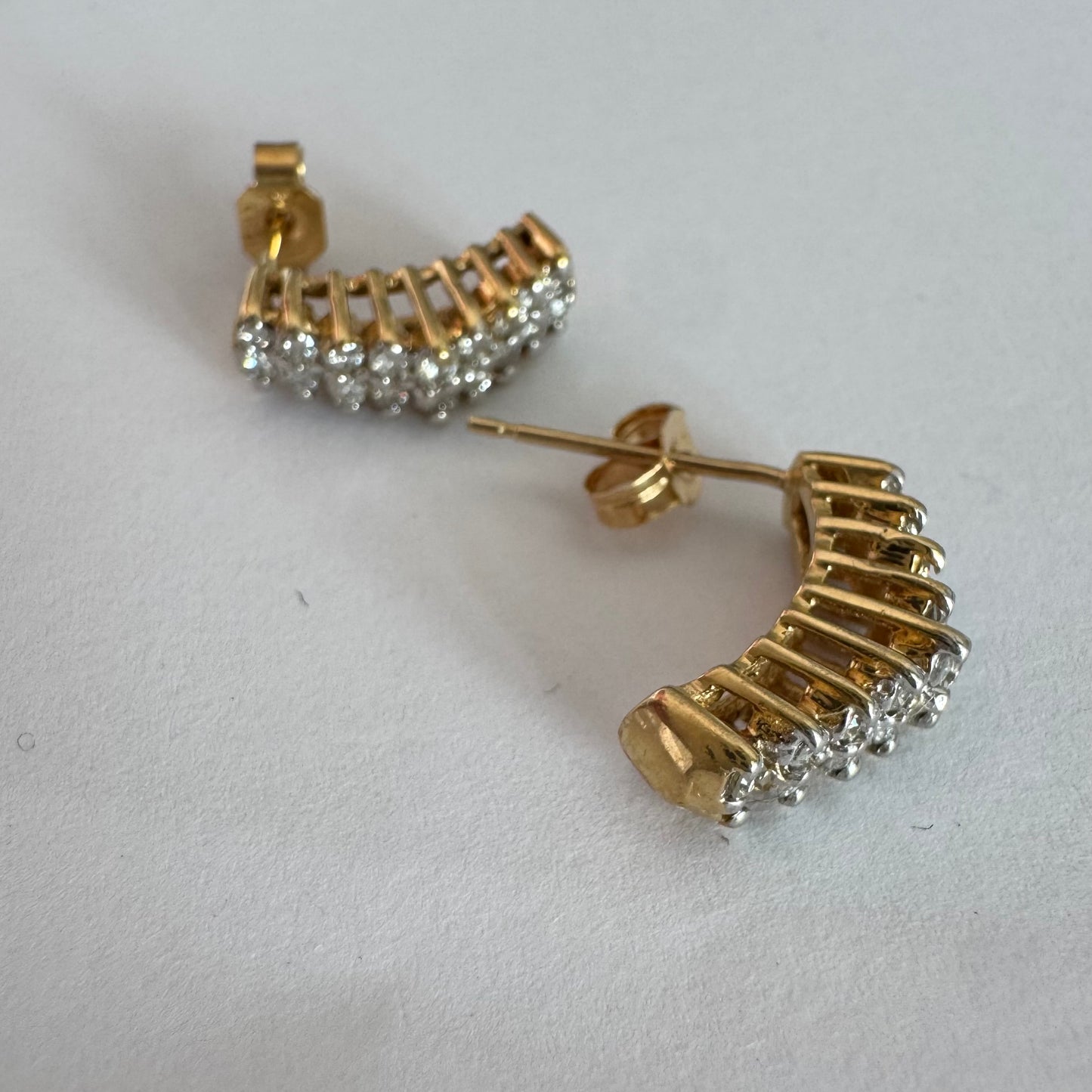 עגילי זהב צהוב 14 קראט בעיצוב חצי חישוק, משובצים יהלומים מנצנצים בשיבוץ צפוף המעניק מראה עשיר ונוכח.