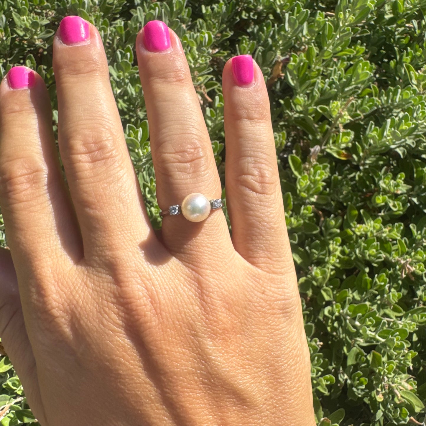 18K gold ring featuring a round Pearl at the center, flanked by two Diamonds.