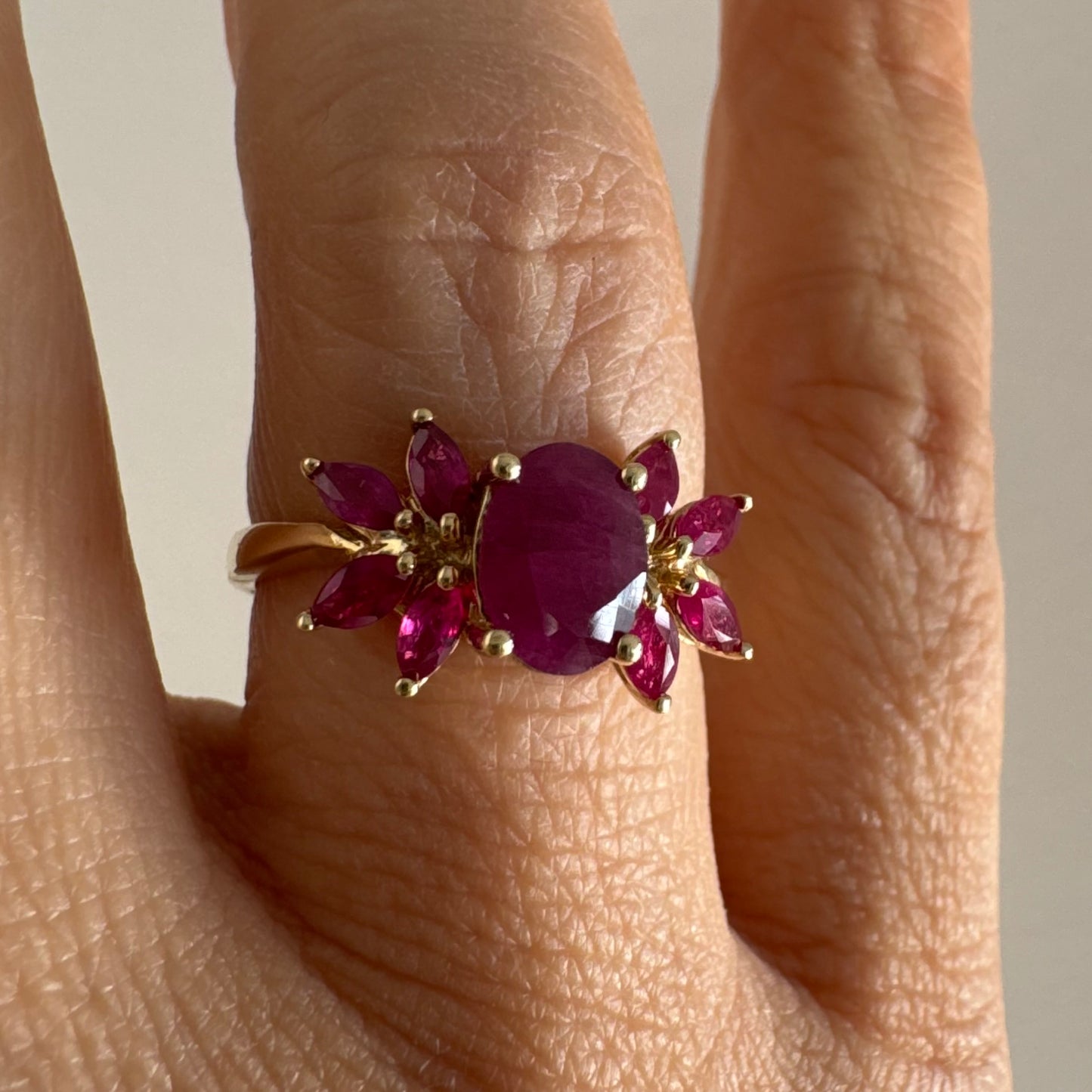 טבעת זהב צהוב 14 קראט משובצת רובי מרכזי גדול ולצידו רובי בחיתוך מרקיזה בעיצוב פרחוני עשיר.