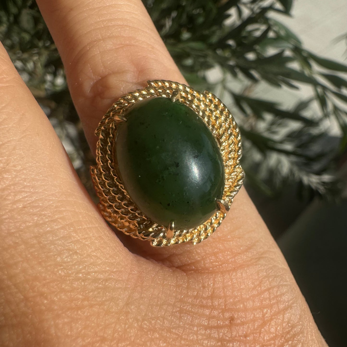 14K gold ring set with a deep green Jade set in a textured gold frame.