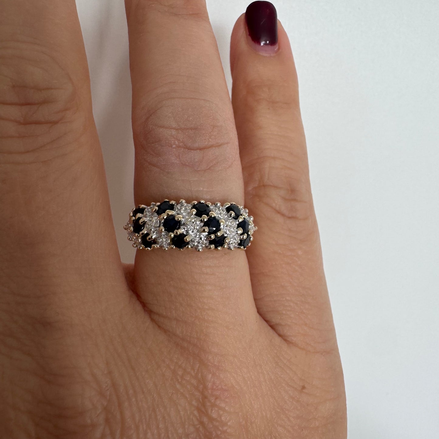 טבעת זהב צהוב 10 קראט משובצת אבני ספיר כהות ויהלומים בעיצוב קלאסי ורומנטי.