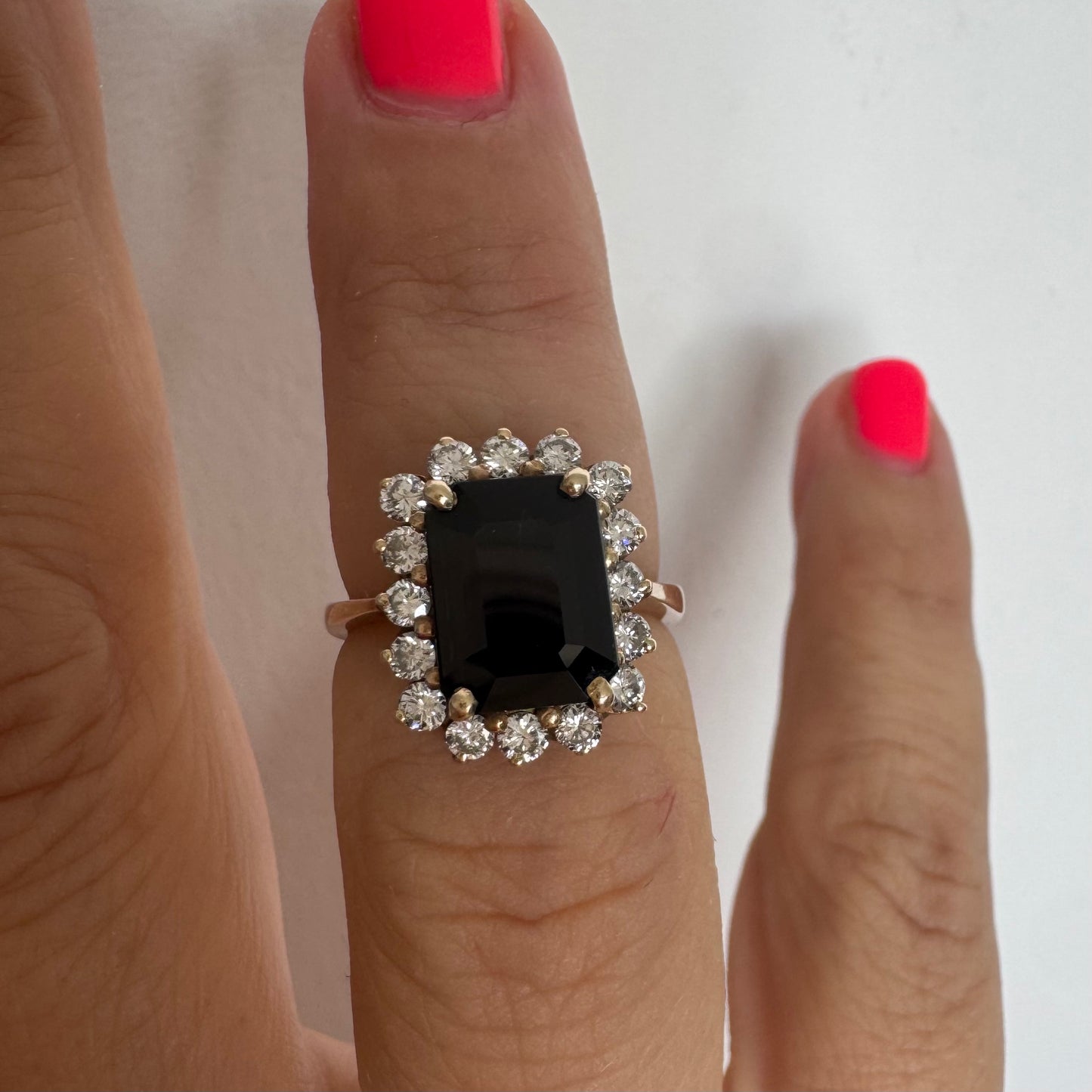 טבעת זהב צהוב 9 קראט משובצת אבן ספיר כחולה מרכזית ומוקפת יהלומים נוצצים.