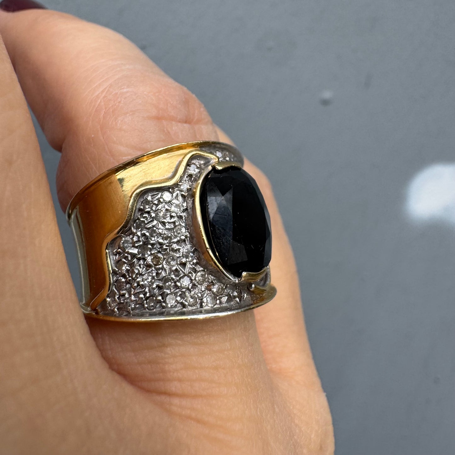 טבעת זהב צהוב 18 קראט משובצת יהלומים ואבן ספיר בצבע כחול כהה במרכז בעלת עיצוב דרמטי ואלגנטי בסגנון וינטג׳-יוקרתי