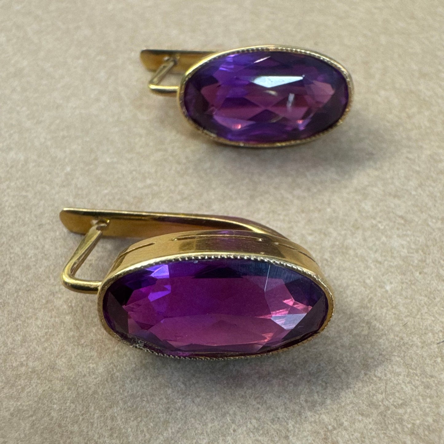 עגילי זהב צהוב 18 קראט, תלויים קצרים, משובצים באבני אמטיסט סגולות בחיתוך אובלי עמוק.