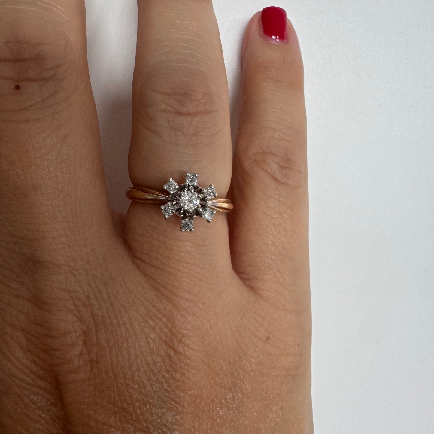 טבעת זהב 9 קראט משובצת יהלום מרכזי ויהלומים מסביב בעיצוב פרח קלאסי.